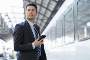 Businessman with cell phone on station platform