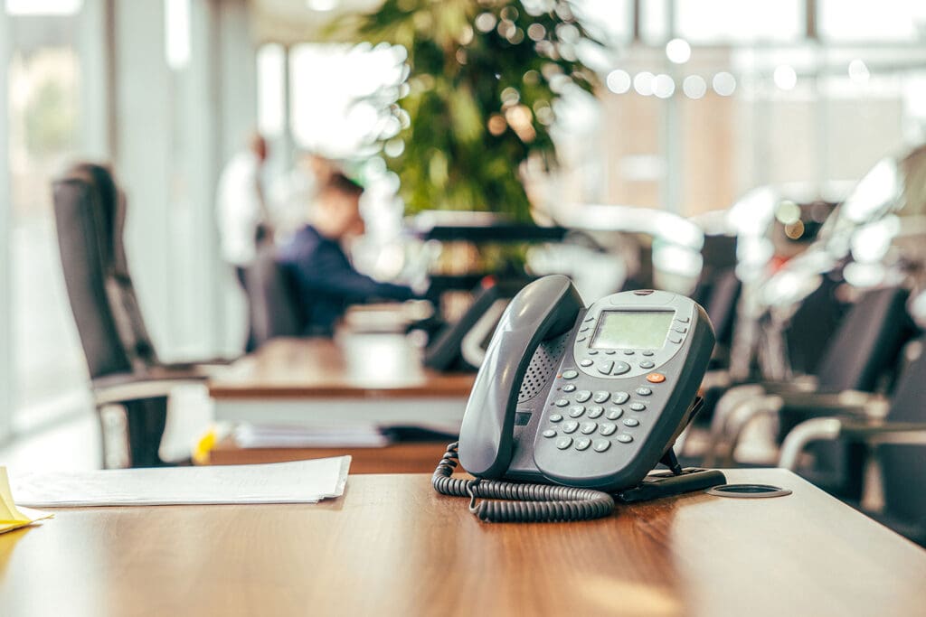 A black office phone sits on a conference table